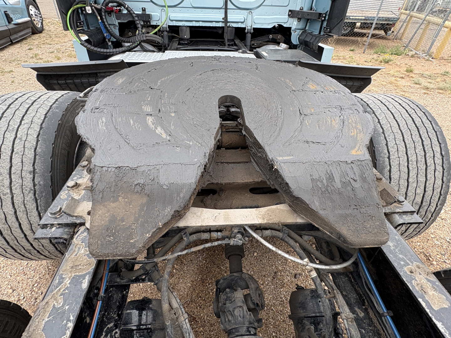 Freightliner Cascadia 126 tractor rear view showing fifth wheel and undercarriage with mud and wear on the plate.