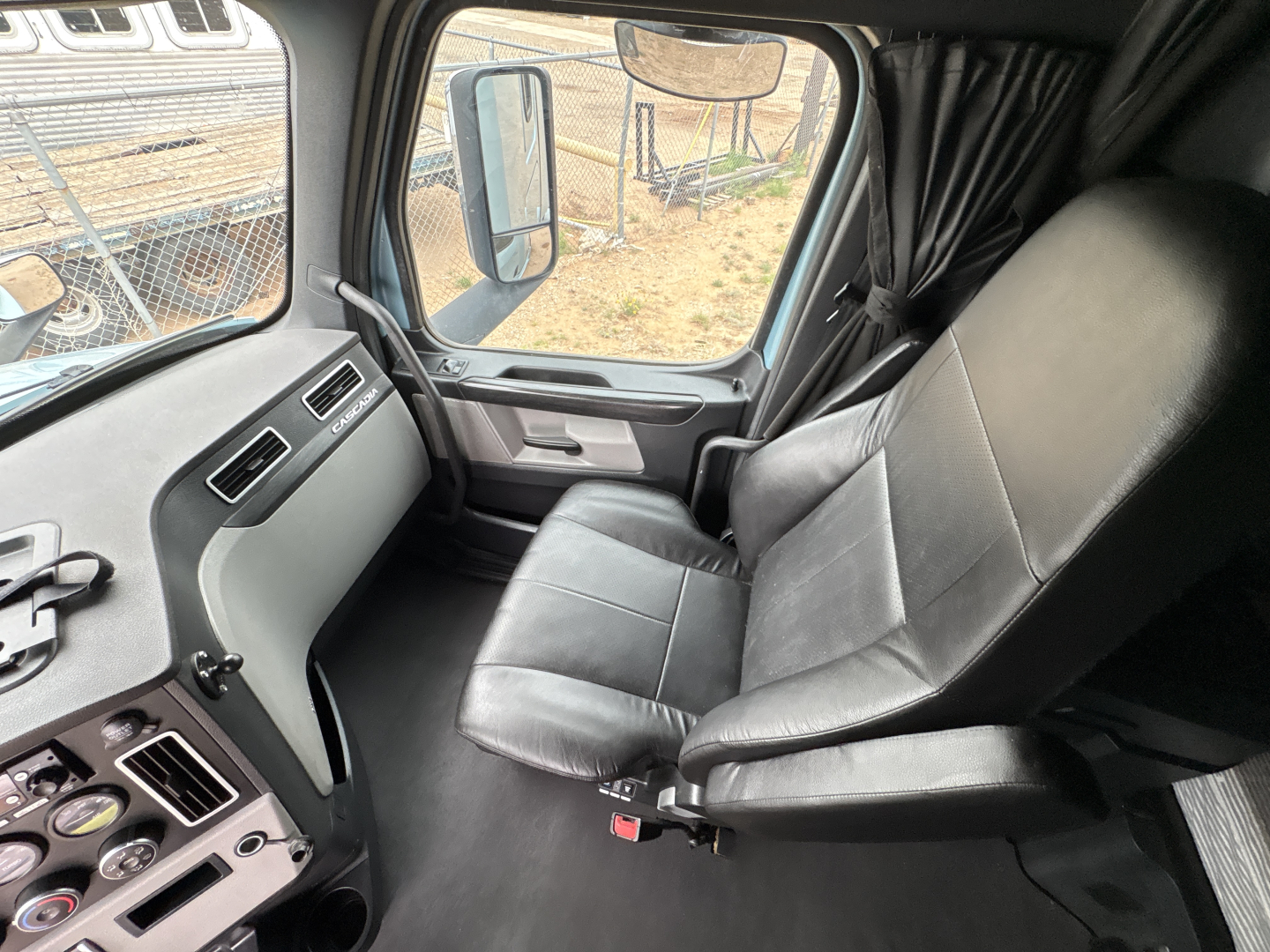 Cab interior of a Freightliner Cascadia truck showing driver's seat and dashboard area.