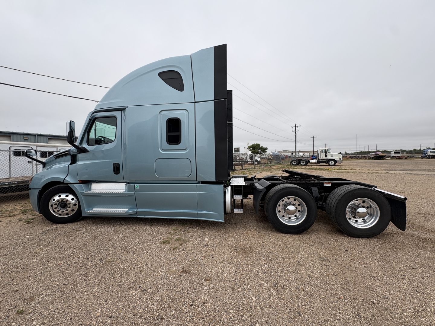 Freightliner Cascadia 126 tractor cab in blue-gray side view showing sleeper cab and attached rear chassis with dual rear axles.