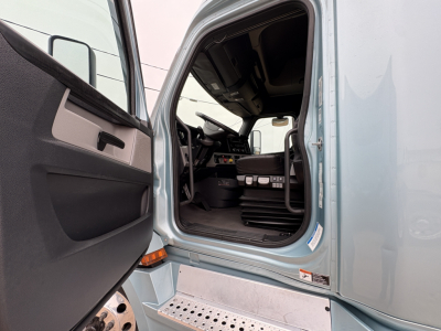 Cab interior view of a Freightliner Cascadia 126 truck with open driver door showing dashboard, steering wheel, and steps.