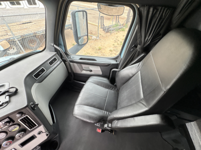 Cab interior of a Freightliner Cascadia truck showing driver's seat and dashboard area.