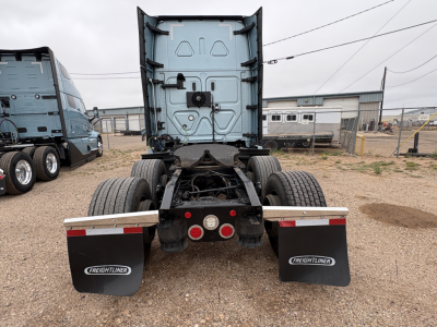 Truck rear view showing fifth wheel and dual rear axles of a Freightliner Cascadia 126 sleeper tractor with mud flaps and bumper reflectors.