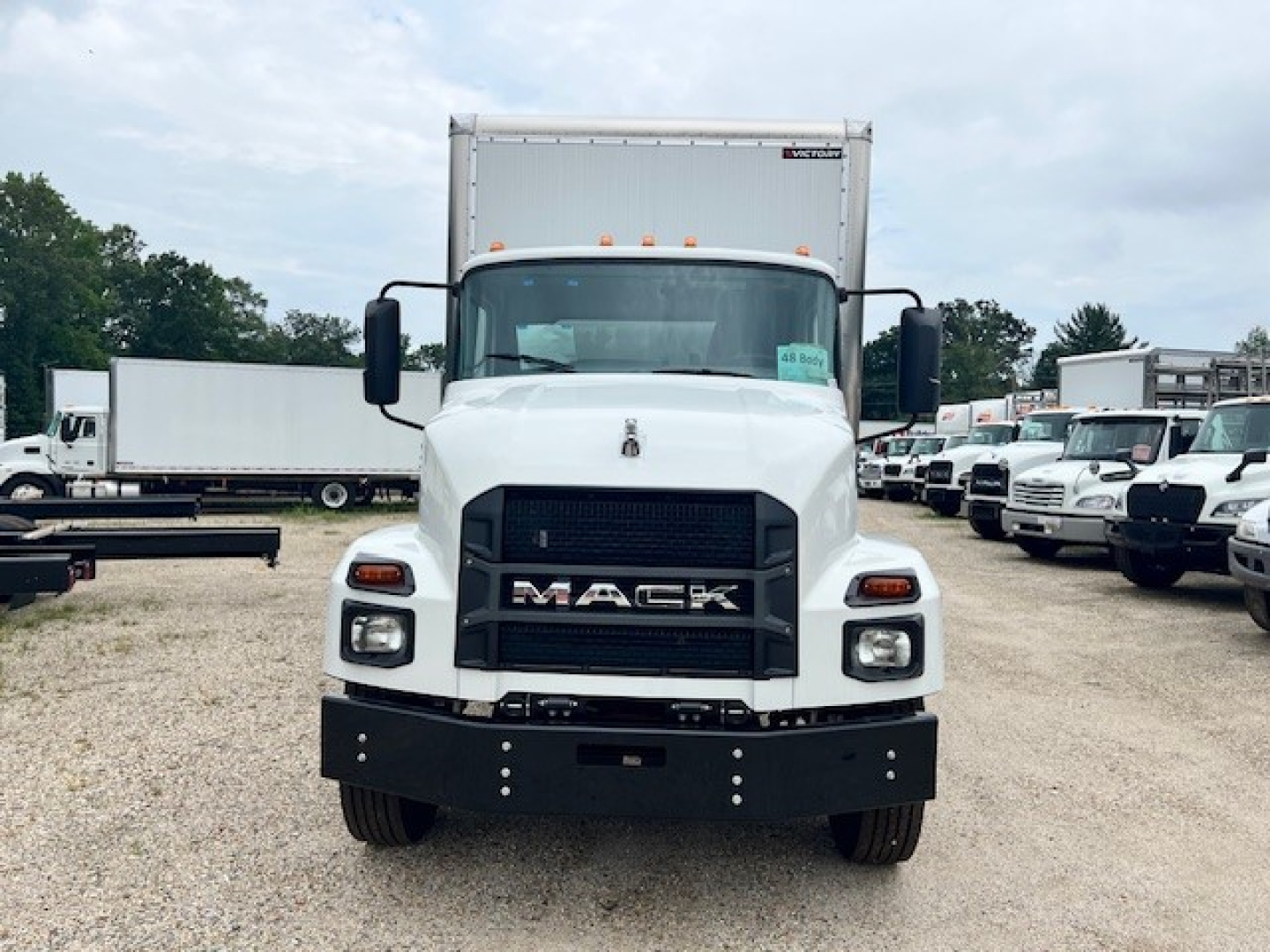 Front view of a white 2025 Mack MD6 box truck with black grille and bumper, showing MACk logo and headlights.