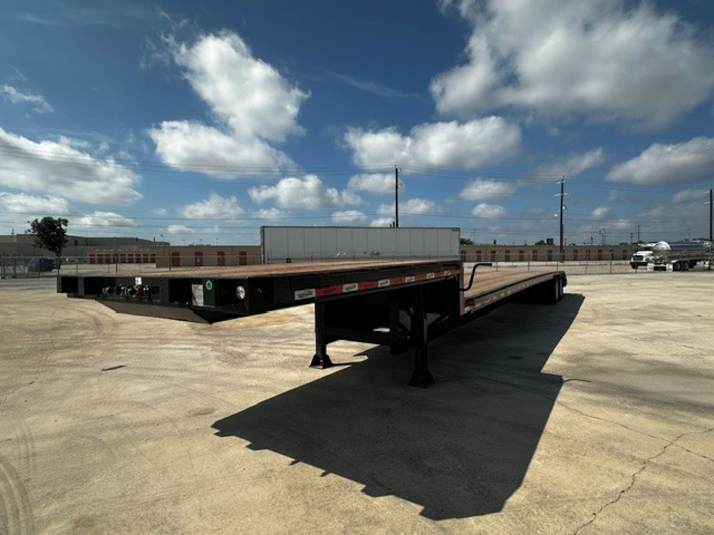 Trailer deck showing closed tandem drop deck trailer with side ramps and landing legs.