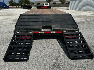 Trailer rear view showing closed tandem drop deck with dual folding ramps extended on each side.