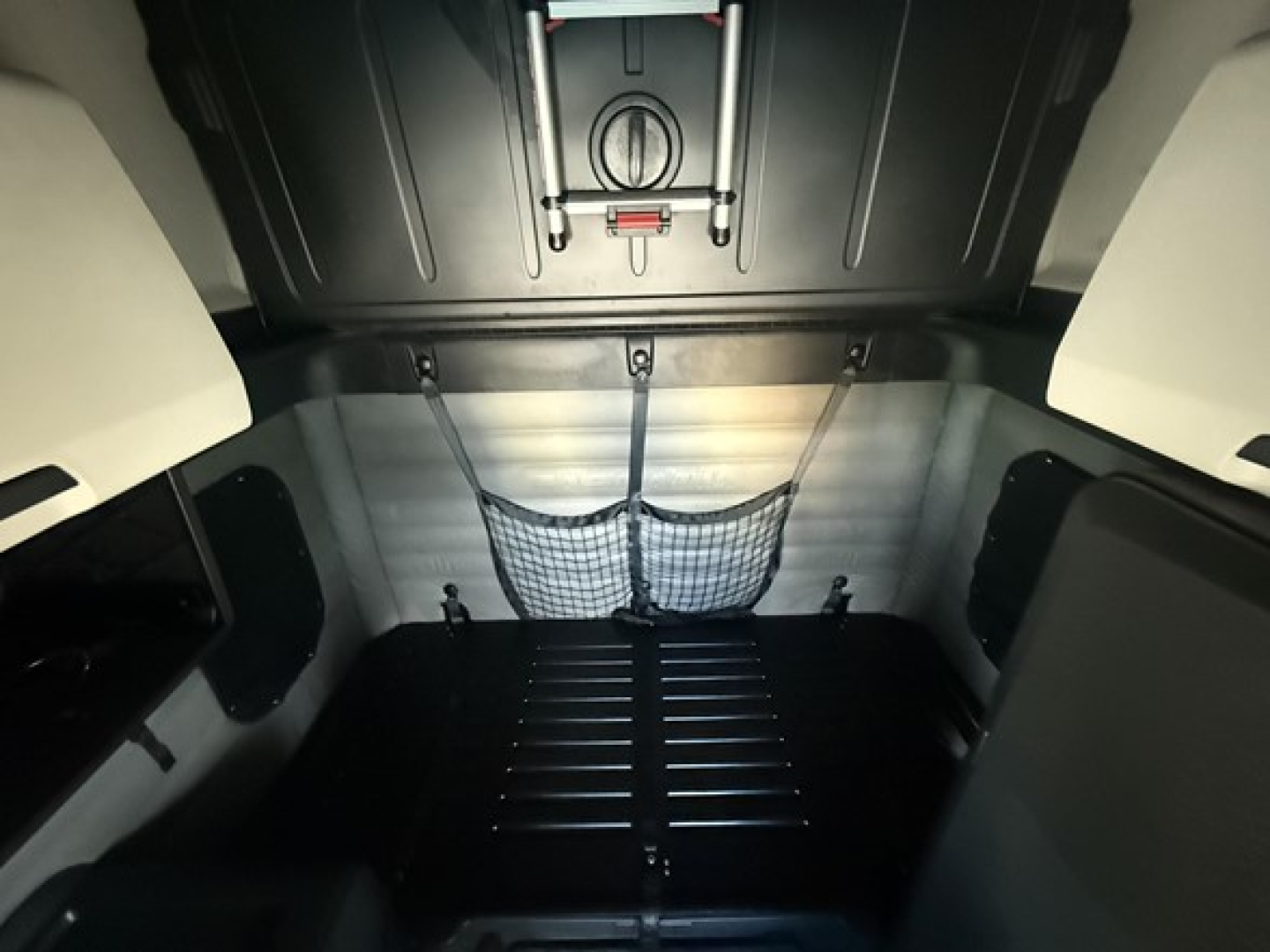 Sleeper cab cargo area of a Freightliner Cascadia 126 tractor showing rear wall with cargo net and overhead insulation; no legible text/signage visible.