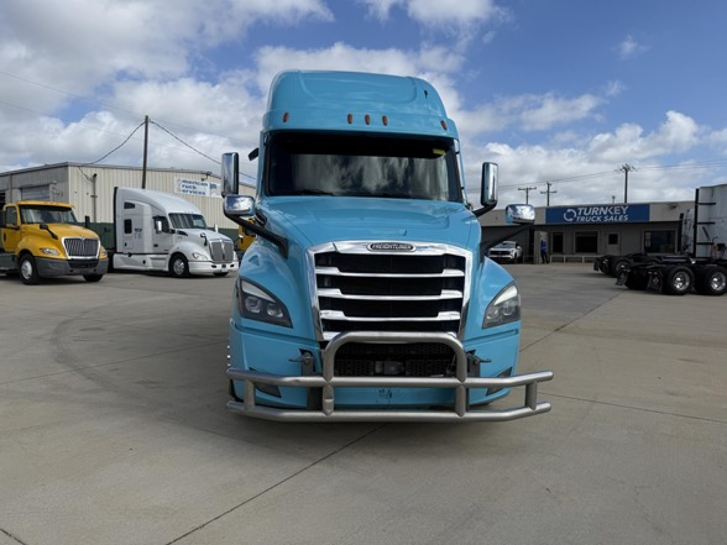 Freightliner Cascadia 126 front view showing chrome grille, bumper guard, large headlights, blue cab, and hood with emblem.