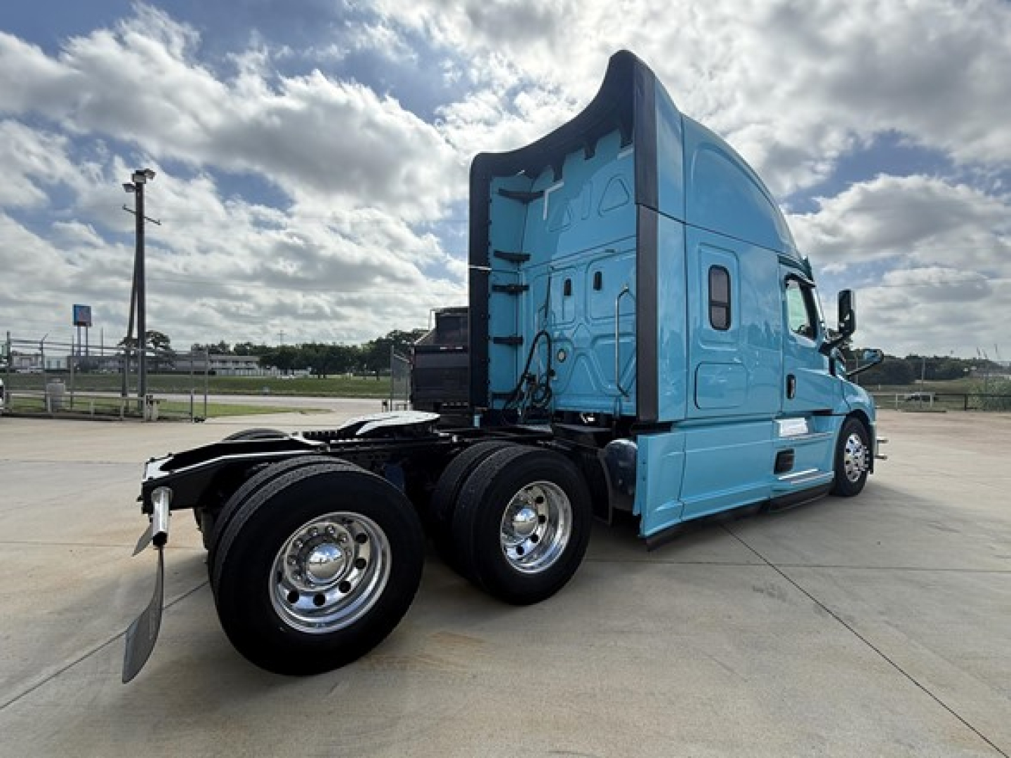 Truck cab and chassis of a blue Freightliner Cascadia 126 tractor, side view, with sleeper cab and dual rear axles.