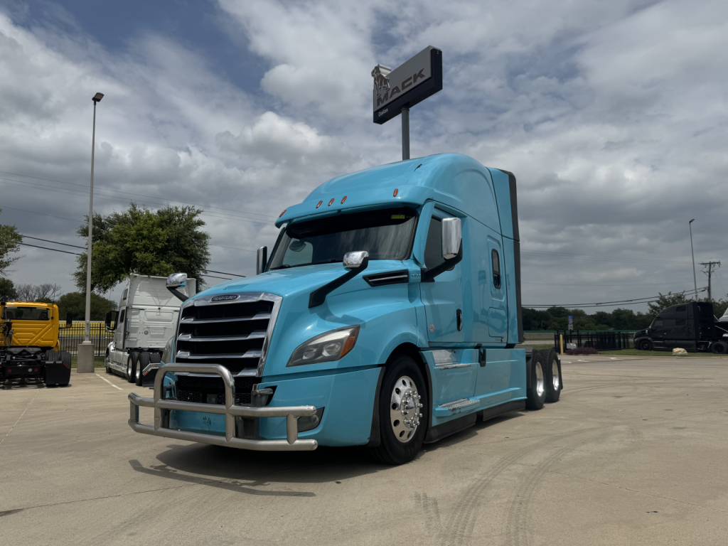 Truck cab showing a blue 2023 Freightliner Cascadia 126 conventional sleeper with chrome bumper guard and mirrors
