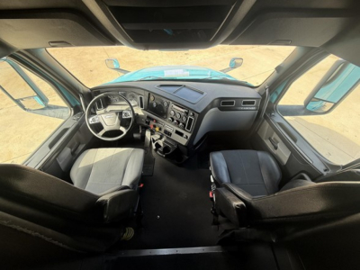 Cab interior of a Freightliner Cascadia 126 with steering wheel, dash controls, and driver and passenger seats visible