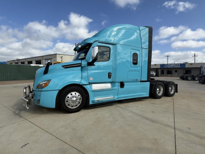 Truck side view showing bright blue 2023 Freightliner Cascadia 126 with sleeper cab and chrome wheels.