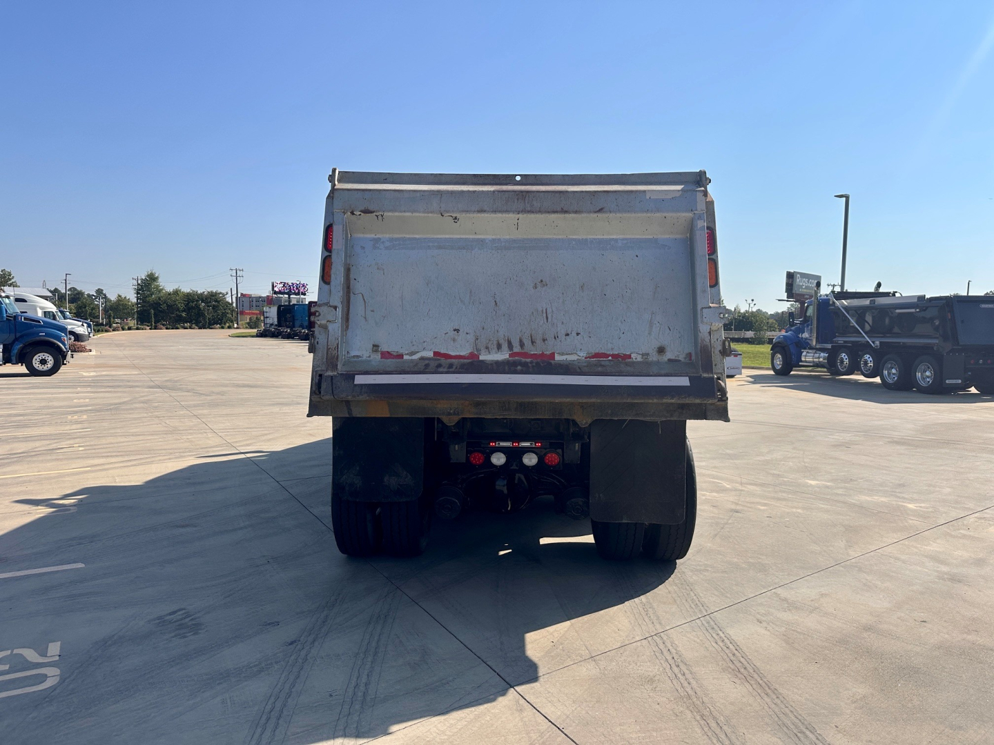 Rear view of a dump truck bed on a 2021 Kenworth T880 with visible mud flap, taillights, and dump bed frame.