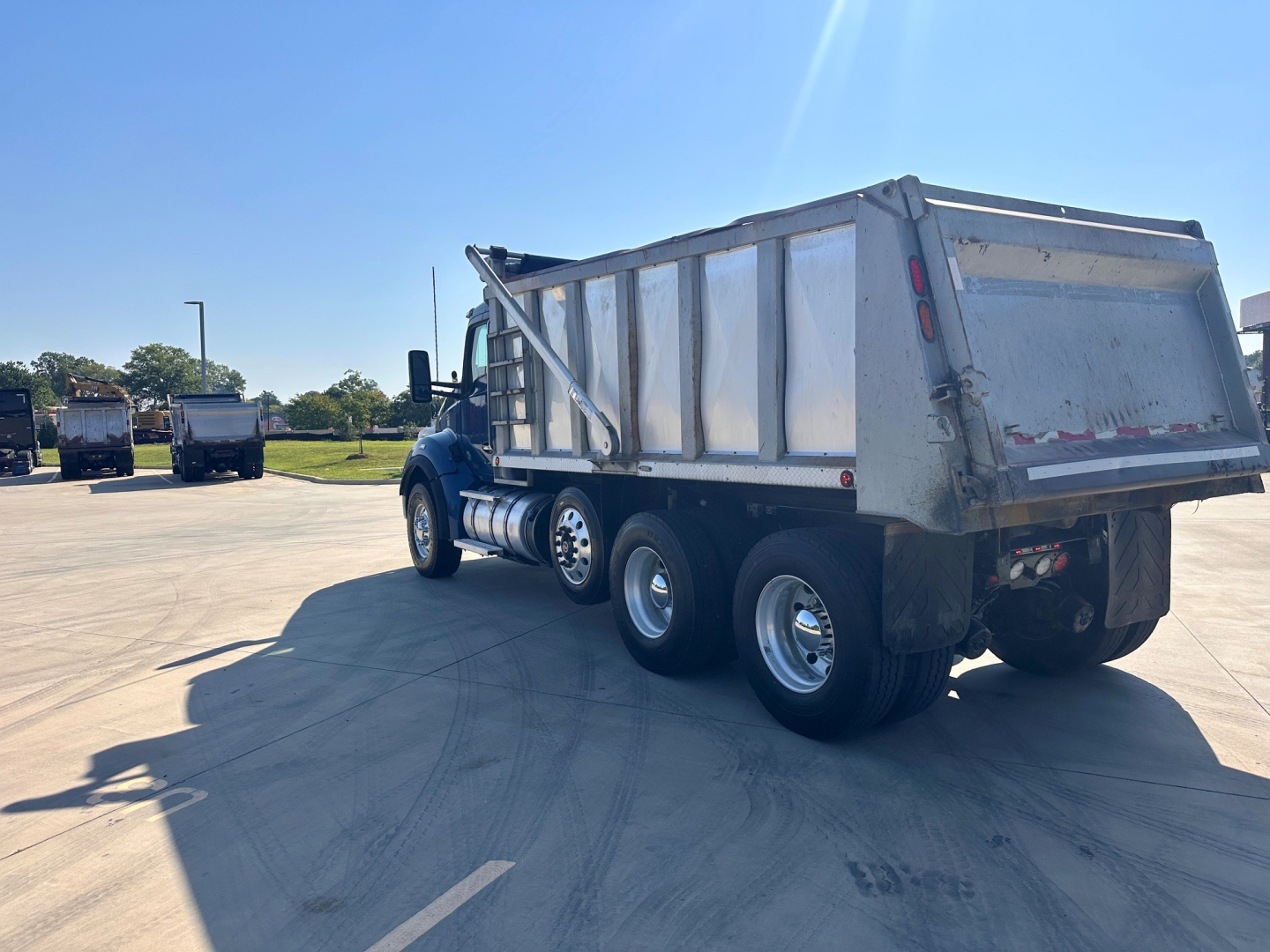 Kenworth T880 dump truck in service with aluminum dump bed, side view showing dual rear axles and side fuel tanks.