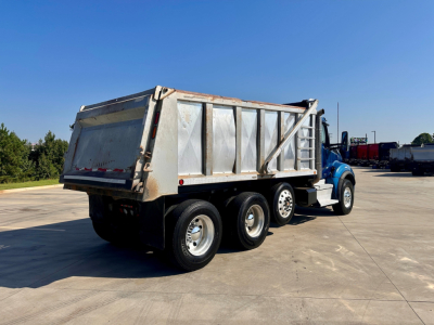 Kenworth T880 dump truck side rear view showing dump bed and three rear axles