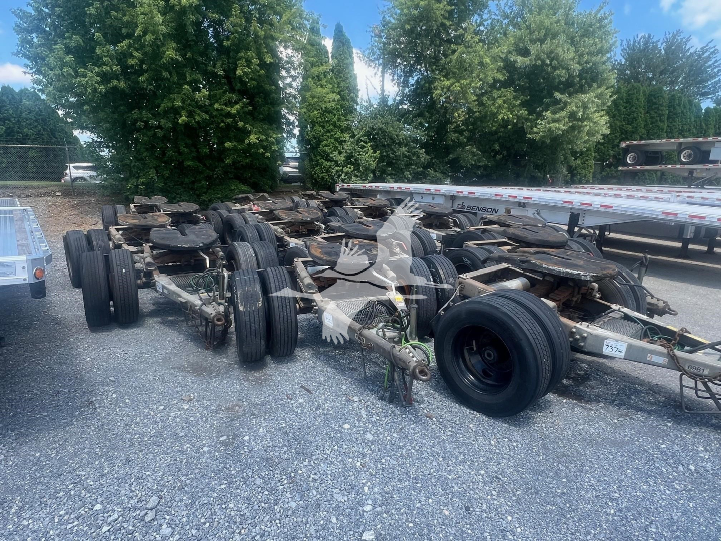 Trailer dolly chassis with multiple axles and wheels in an outdoor lot.