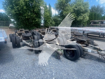 Trailer dolly chassis with multiple rear axles and tires visible; overlay watermark shapes across image.
