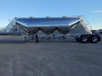 Pneumatic dry bulk trailer by Mac showing polished aluminum finish and tandem axles.