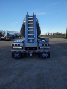 Mac Pneumatic trailer rear view showing loading ramps and dual axles with Mac logo mudflaps.