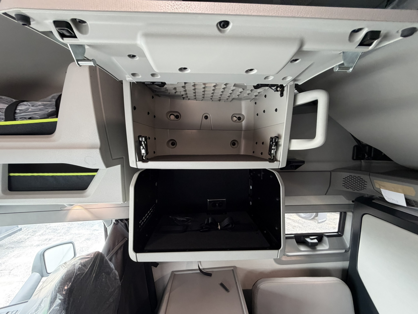 Truck cab storage compartments in a Volvo VNL64T860 sleeper showing overhead locker and open bunk/compartment with metal mounting rails.