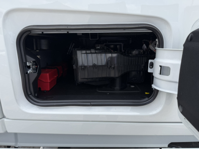 Volvo VNL64T860 cab side storage bay showing engine components and battery in bay.