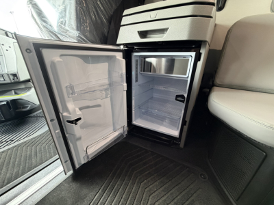 Fridge/freezer unit in a Volvo VNL64T860 cab showing open mini refrigerator/freezer with empty shelves.