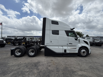Volvo VNL64T860 tractor in profile view showing sleeper cab, white paint, and tandem rear axles. Clear VIN/stock not visible on tag.