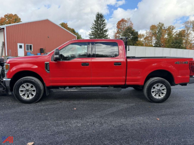 Ford F-250 Super Duty pickup truck side view in red with crew cab and long bed, 4x4 badge visible, plow-ready heavy-duty vehicle.