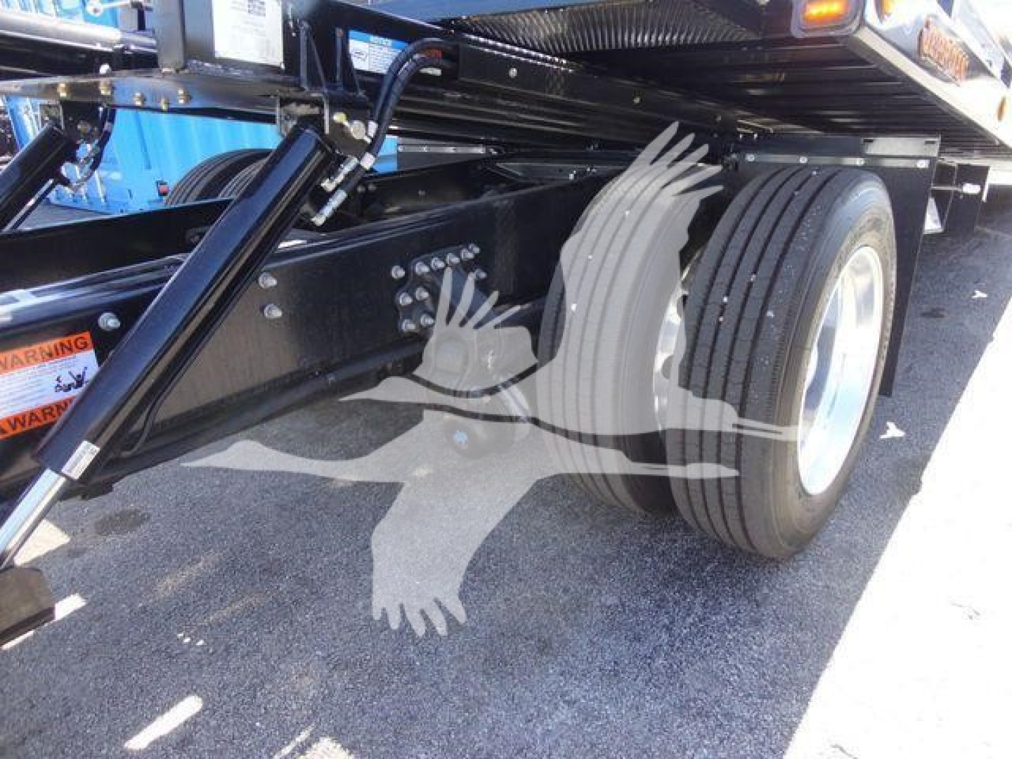 Truck undercarriage showing rear dual wheels and suspension components of a Mack MD6 rollback truck.
