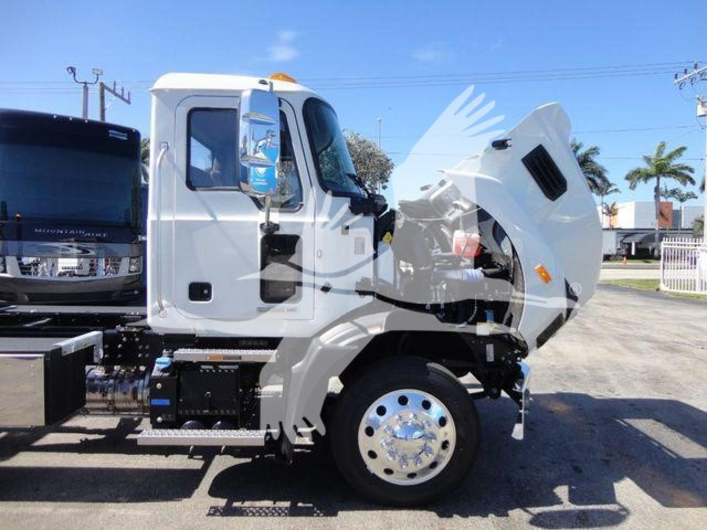 Truck engine bay showing large white cab with hood open and exposed engine components.