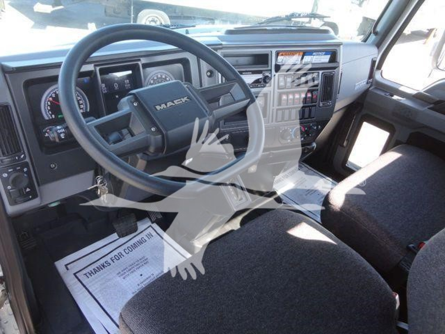 Truck cab interior of a 2027 Mack MD6 showing steering wheel, dashboard, and driver seat.
