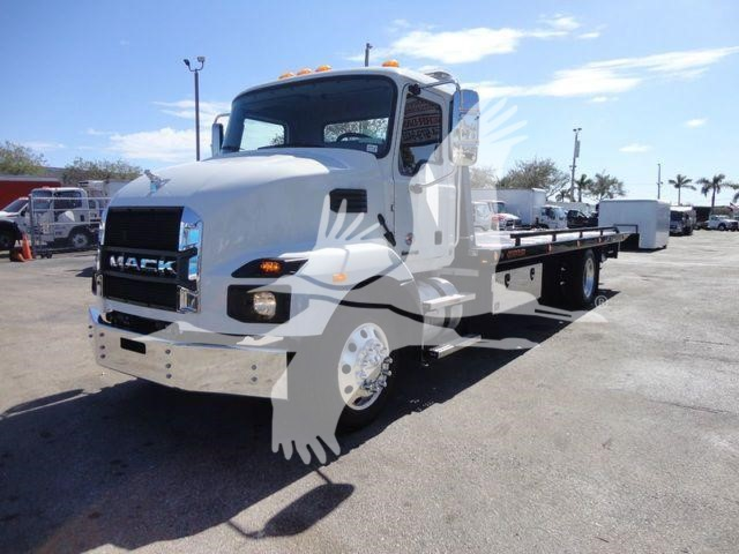 Mack MD6 rollback truck in a dealership lot, front-left view, white cab, flatbed with wheel lift, stock number WHTMACKMD6 visible in listing.