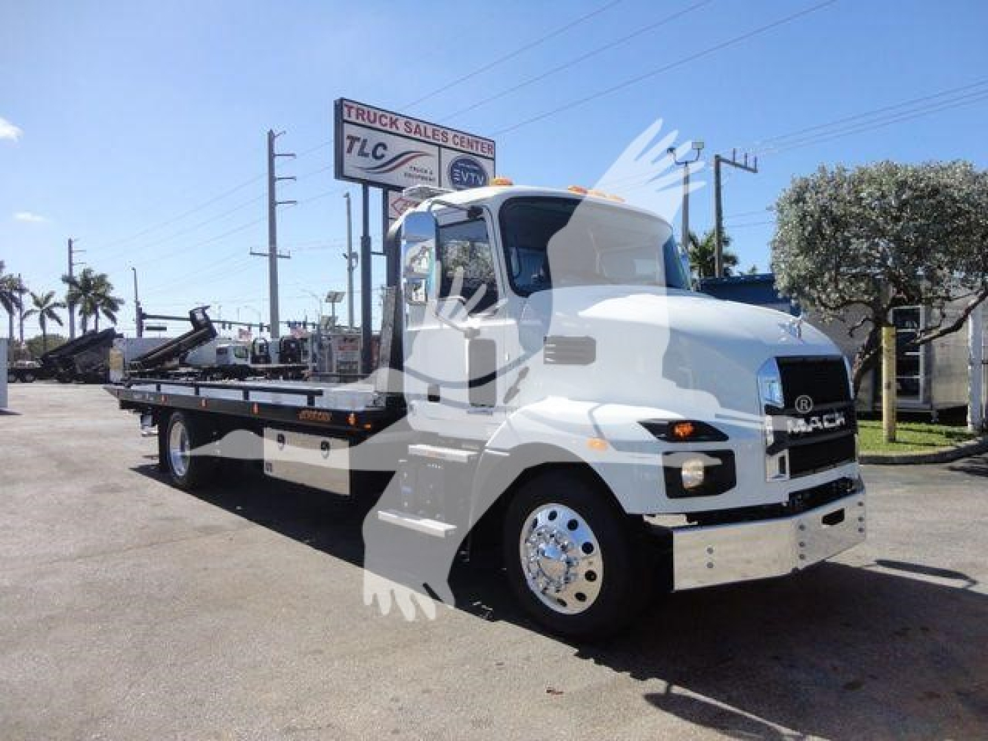Mack MD6 rollback truck shown in side/front angle with white cab and flatbed, chrome bumper, and rolling rear wheels.