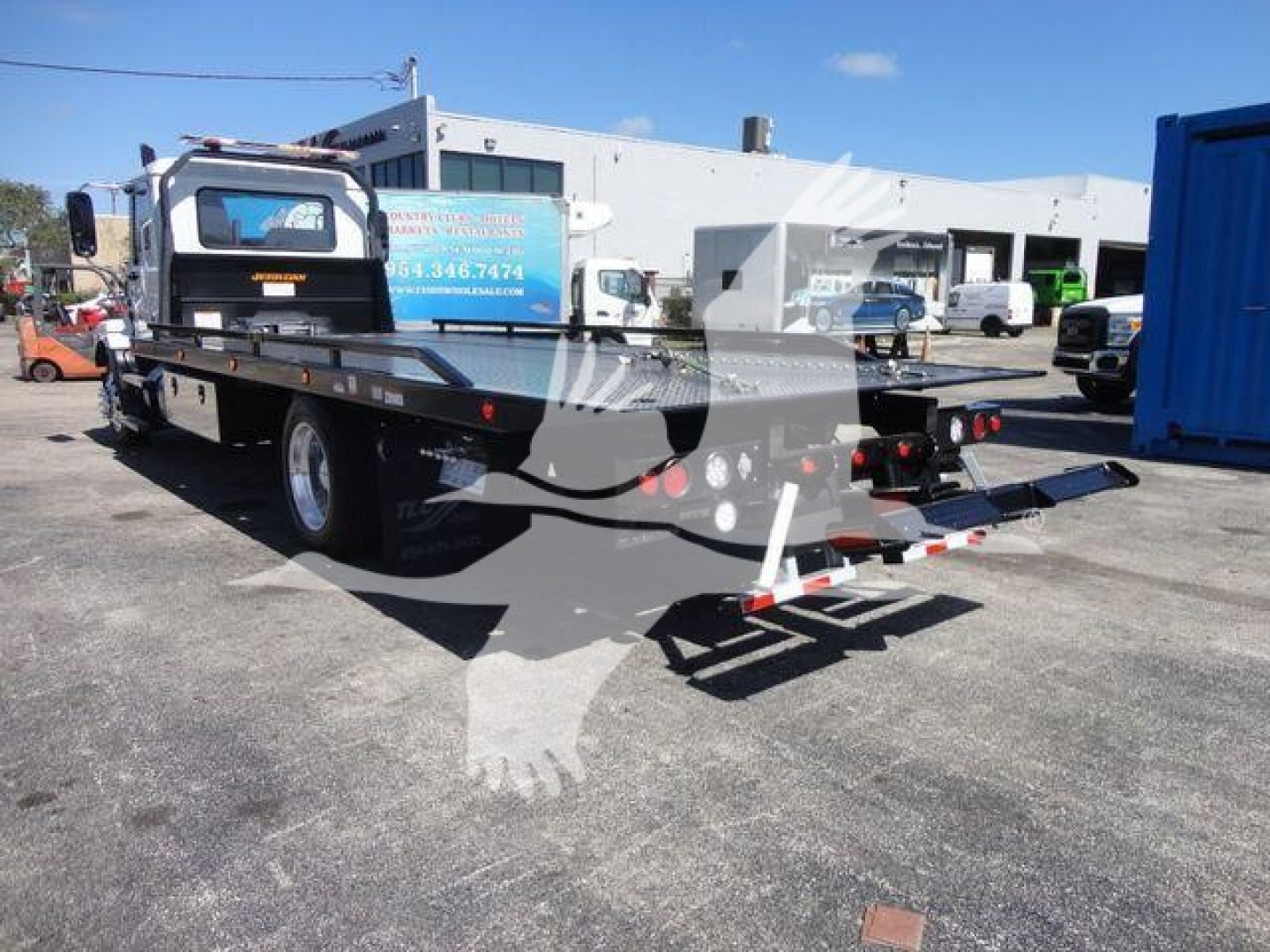 Mack MD6 rollback tow truck rear and side view showing flatbed and ramps with clear labeling and equipment.