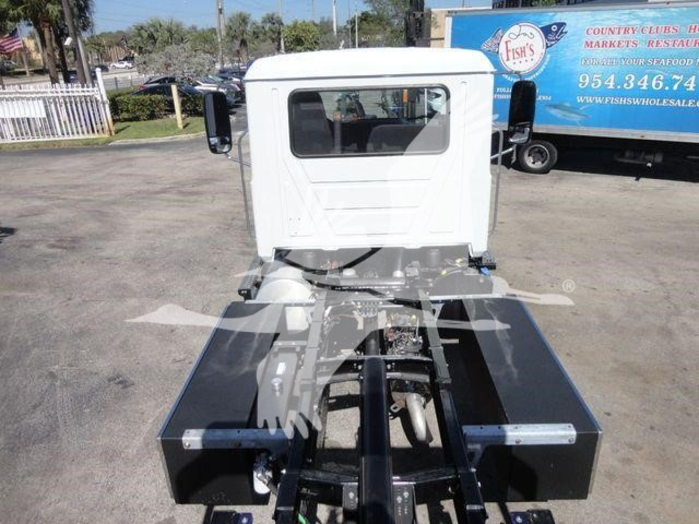 Mack MD6 cab-over truck chassis in a yard showing the rear frame and fifth-wheel area, white cab, black chassis with metal components.