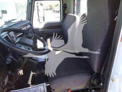 Truck cabin interior of a 2027 Mack MD6, front seats and steering wheel visible, dashboard and side window, with a white bird watermark across image.