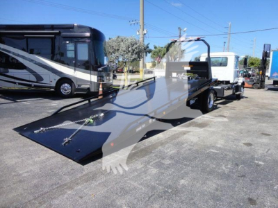 Truck with a flatbed rollback equipment showing a large black ramp and a white truck cab attached; license/stock text not visible on image; no legible labels.