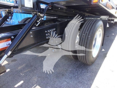 Truck undercarriage showing rear dual wheels and suspension components of a Mack MD6 rollback truck.