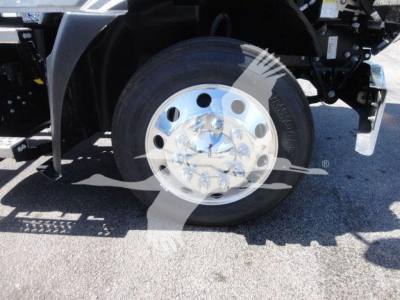 Front wheel of a Mack MD6 rollback truck showing a polished metal hubcap and tire.