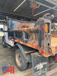 Ram 5500 dump truck rear view with rusted hydraulic dump bed and winch hook, undercarriage and taillights visible.
