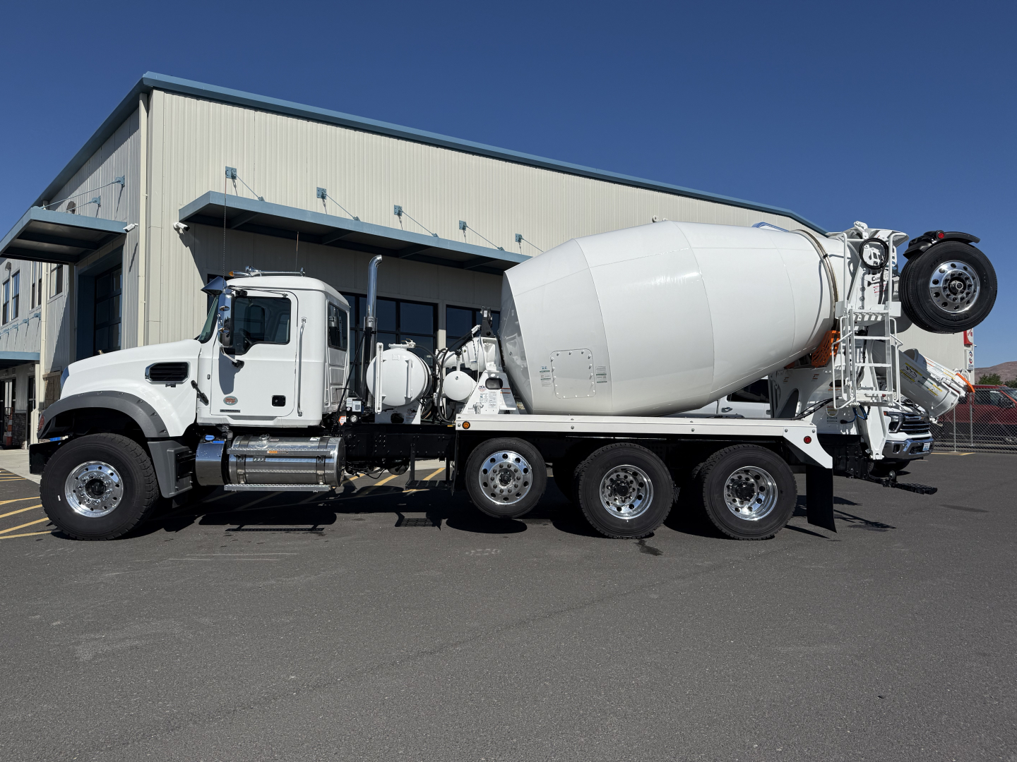 Concrete mixer truck with a white cab and large rotating drum, side view showing mixer body and rear wheel assembly.