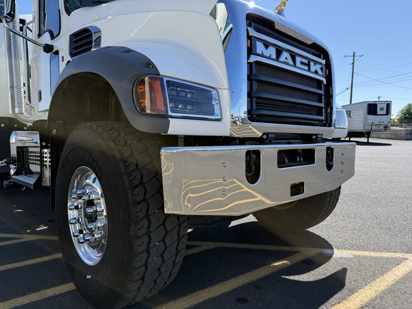 Mack GR84F mixer truck front view showing chrome bumper and heavy-duty tire in daytime light.