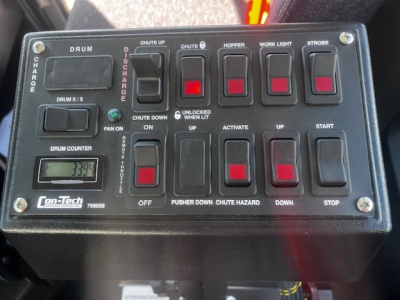 Control panel of Mack mixer truck with labeled switches and a small display reading '1339' or similar; includes labels DRUM, CHARGE, CHUTE UP, CHUTE DOWN, HOPPER, WORK LIGHT, STROBE, FAN ON, UP, START, STOP, OFF, ON, DOWN, CHUTE HAZARD, PUS