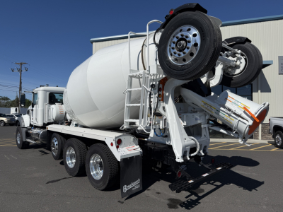 Mixer truck rear with concrete mixer drum and mounted lifting equipment on a white Mack GR84F chassis in a lot.
