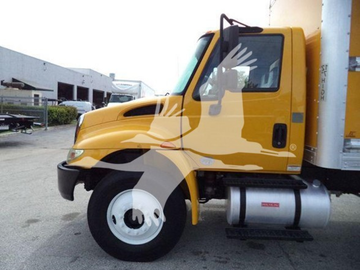 Side view of 2018 International Durastar 4300 box truck in yellow with cab and front wheel visible.