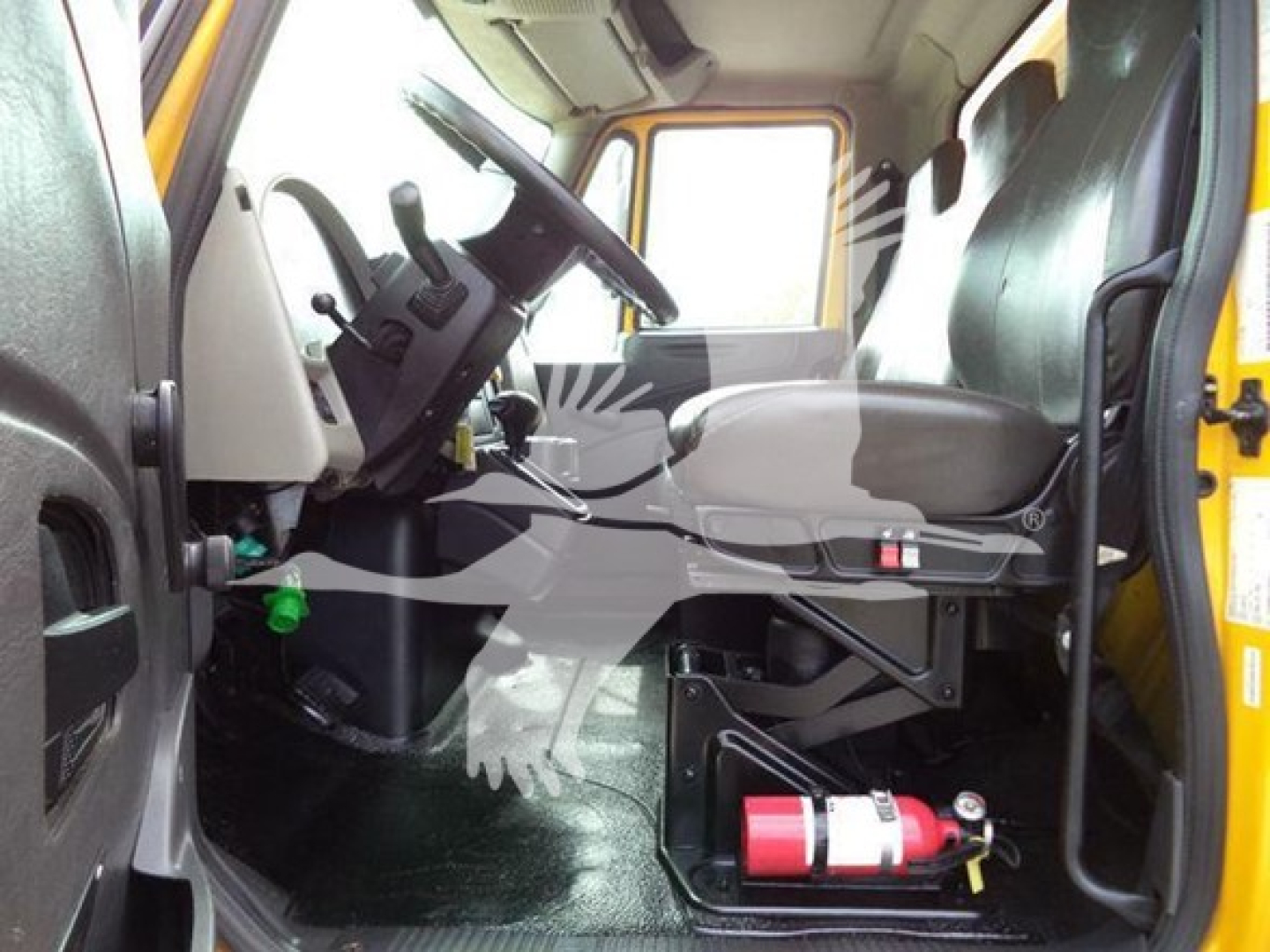 Cab interior of a 2018 International Durastar 4300 box truck showing driver seat, steering wheel, pedals, and a red fire extinguisher mounted near the floor.
