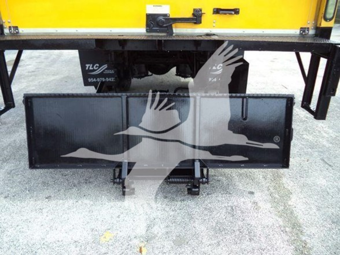 Truck rear showing hitch and a black rectangular toolbox/rack beneath a yellow Durastar 4300 cab. Visible text includes TLCs and contact numbers on the plate.