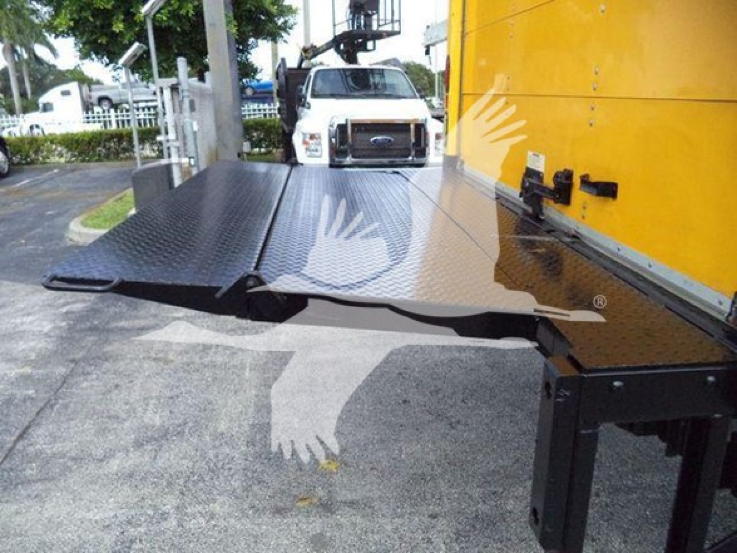 Truck bed ramp on a 2018 International Durastar 4300, metal diamond plate platform visible with yellow cab in background.