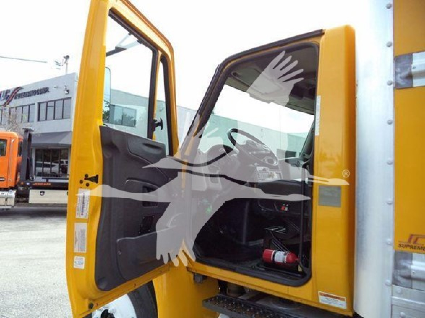 Truck cab interior and doorway of a yellow 2018 International Durastar 4300 box truck showing open driver door with interior panel and step.