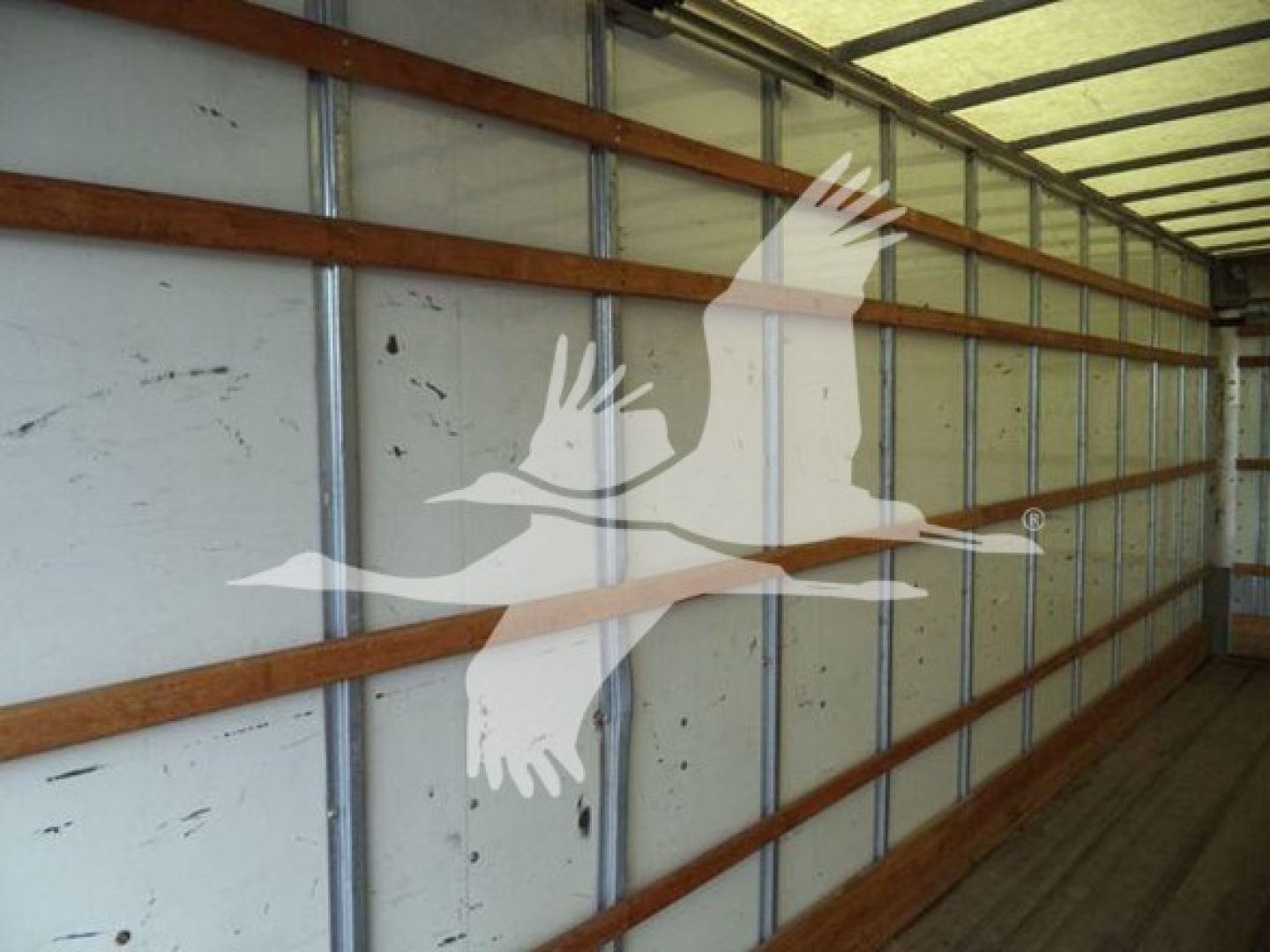 Interior of a box truck cargo area with metal walls and wooden support slats, showing no text labels visible.