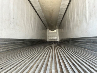 Reefer trailer interior showing ribbed flooring and side walls with ceiling heat duct, empty cargo space.